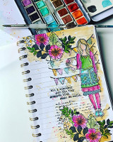 Art journal page with Cari colored in bright pink, green and aqua under the bunting, framed by pink flowers and leaves on a yellow watercolor wash.