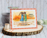 Card with the two friends in blue and green on a warm sunset beach, framed in coral over a wood slice, sentiment "KINDNESS comes in many forms but always from the heart."