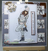 The girl in a plaid outfit on a gray snowflake card with a die-cut snowflake, with "Stay warm and cozy."