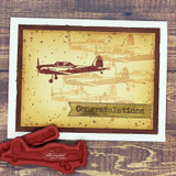 Sepia vintage card with the airplane stamped twice in brown over a “Congratulations” banner, red rubber stamps alongside.