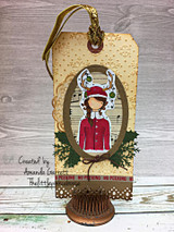 Gift tag with the antlered girl framed in an oval with greenery and glitter accents.