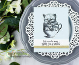 Soft blue-gray kitten in a teacup on a white doily and gray plate with 'life needs more sweet tea & smiles.'