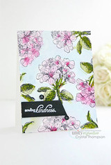 A card covered in pink apple blossoms and green leaves, with a black banner reading 'sending kindness.'