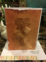 Rust-colored card with the mason jar of flowers stamped tone on tone and a sheer ribbon bow
