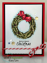 Red-framed white card with a leafy wreath coloured green with a red bow, sequins and a red and white twine bow, sentiment 'Have a cheery Christmas'.