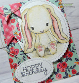 Handmade card featuring the floppy-eared Cuddlebug bunny sitting sweetly, on floral patterned paper, stamped with 'Hoppy Birthday'.