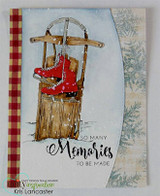 Card on red buffalo plaid and snowflake papers, with the sled colored warm brown and the skates bright red, sitting on a snowy blue arch.