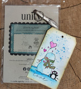 Packaged stamp set beside a snowy tag with the snowman and penguin.