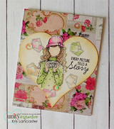Card with the planner girl colored in green tucked inside a big kraft heart on floral papers, with 'every picture tells a story.'