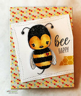 Handmade card featuring the cheery Cuddlebug bumblebee, on orange floral paper with a honeycomb die, stamped with 'Bee happy'.