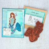 Aqua-framed card with the mermaid in blue and purple, shown beside its Adella Girl packaging and the red rubber stamp.