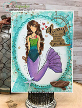 Card with an aqua oval frame and gold accents: the mermaid colored in green and purple beside “always be on the lookout in the presence of wonder.”