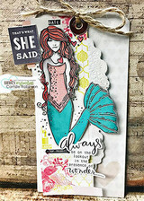 Distressed tag card with twine: the mermaid in teal beneath a “THAT'S WHAT SHE SAID” tile and the presence-of-wonder sentiment.