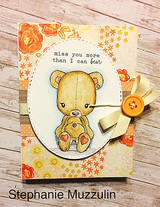 Card with an orange floral background and a cream oval mat, the teddy bear coloured in soft grey and tan with an ochre bow, sentiment 'miss you more than I can bear'.