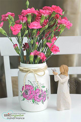Painted mason jar with pink stamped flowers beside fresh carnations
