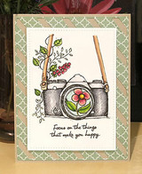 Card with the floral camera colored on green diagonal stripes and 'Focus on the things that make you happy.'