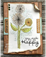 Sample card with the dandelions colored in soft gold and green over a script background on a torn vintage panel, mounted on wood grain paper with brass brads.
