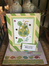 Green striped easel card standing on wicker with two white bird figurines, a tall mojito glass full of lime slices stamped and colored, and a tag reading "sometimes all you need is a mojito."