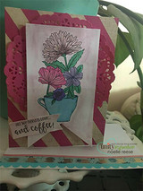 Softly colored flowers in a teacup on a white panel over a pink doily and striped paper with 'all we need is love...and coffee' on a banner.