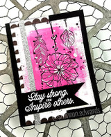 A pink poppy on a black card layered over a chicken-wire background.