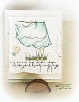 A soft white card with the barefoot girl stamped from the waist down in a windblown mint dress standing in grass, above the sentiment 'May your feet take you where your heart wants to go'.
