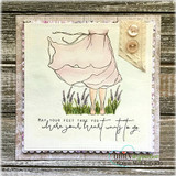 A weathered wood card with the girl in a blush dress standing in lavender, buttons at the corner, above the sentiment 'May your feet take you where your heart wants to go'.