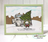 Snowy hills card of a gray truck with wreath and tree in a green frame.