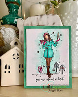 Card with the girl in a teal coat on a green stitched frame with a cozy house nearby.