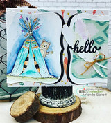 Card with a teal and blue watercolor teepee and bear on a curved panel beside a large hello die-cut and ikat paper.