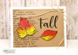 A kraft card with the fall sentiment repeat stamped as a background pattern, two bright orange and red leaves in the center and brush lettered 'Fall' beside them.