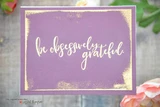 A purple card with gold torn edges and the sentiment 'be obsessively grateful.' brush lettered in white across the center.