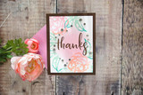 A brown framed card with a pastel blended panel and 'thanks' brush lettered in black, styled with peach roses.
