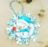 Sketchy snowman in a blue hat holding a red bird, layered on a die-cut snowflake ornament.