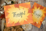Two orange and gold cards with soft leaf silhouettes stamped over sunset toned backgrounds, each finished with Thankful for you in pale lettering.