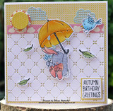 Lavender die-cut card with the bunny under a golden umbrella among clouds, a sun and a blue bird, finished with a tag reading Autumn birthday greetings.