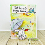 Yellow and green watercolor card with the bunny under a pale umbrella, a teal bird and a red leaf, topped with a kraft panel reading Fall breeze and Bright Leaves.