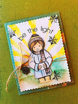 Green card with the girl in soft neutrals against yellow sun rays with silver snowflakes, twine and a pinecone, and be the light in an arc.