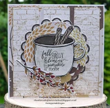 Card with a white brick background and a golden die cut wreath, a grey enamel mug with cinnamon sticks stamped 'fall breeze autumn leaves pumpkins please' and a berry sprig.