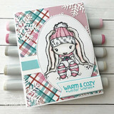 Bunny in a pink knit hat inside an oval over pink and teal plaid paper with a cozy winter greeting, shown with markers.