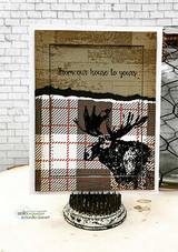 Card with the barn wall and plaid behind a moose: 'from our house to yours.'
