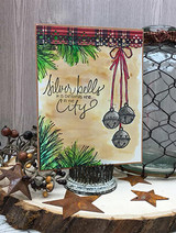 Handmade card featuring the strand of jingle bells and a sprig of holly berries, among pine and rusty stars, stamped with 'Holiday hugs & mistletoe kisses'.