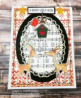 Card with red folk print papers and a black oval frame over sheet music, two deer coloured in tan with a small red house and a merry little wish label above.
