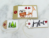 A kraft card with the deer and cart colored in tan, paired with a tag of green pine trees and a cloud tag reading 'joyful'.