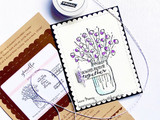 Scalloped white card with purple flowers in the jar beside Graciellie Design packaging