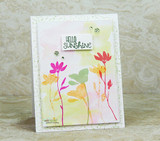 The swirl background softly inked behind bright stamped flowers — 'hello sunshine.'