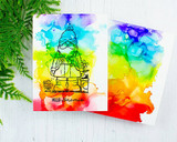 Two alcohol ink cards in bright rainbow blends on a white background with a fern, the gnome stamped in black over the vivid colour wash and "HELLO gnomie" stamped underneath.