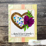 Patterned card in peach and green with the twig heart filled with sequins and a magenta bloom, above a script strip reading Here's to love and friends.