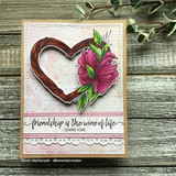Grey wood card with the twig heart in rich browns and a fuchsia lily, above a script panel reading Friendship is the wine of life.