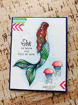 Navy-framed card with the mermaid colored in copper hair and a green and teal tail, drifting above pink jellyfish, over 'She is brave and full of love.'