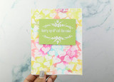 Rainbow watercolor hearts background on a white card with a green cake greeting panel.